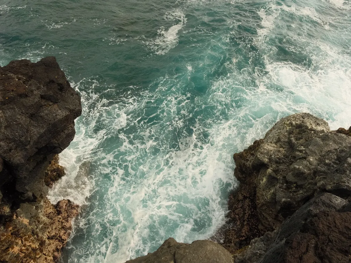 Waves breaking against the volcanic rocks of the Souillac coast